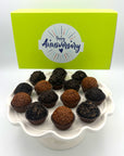 Anniversary Chocolate Lovers Brigadeiros, beloved by chocolate lovers worldwide, are delicately placed on a white plate alongside a charming yellow box, making them a perfect treat for any anniversary celebration.
