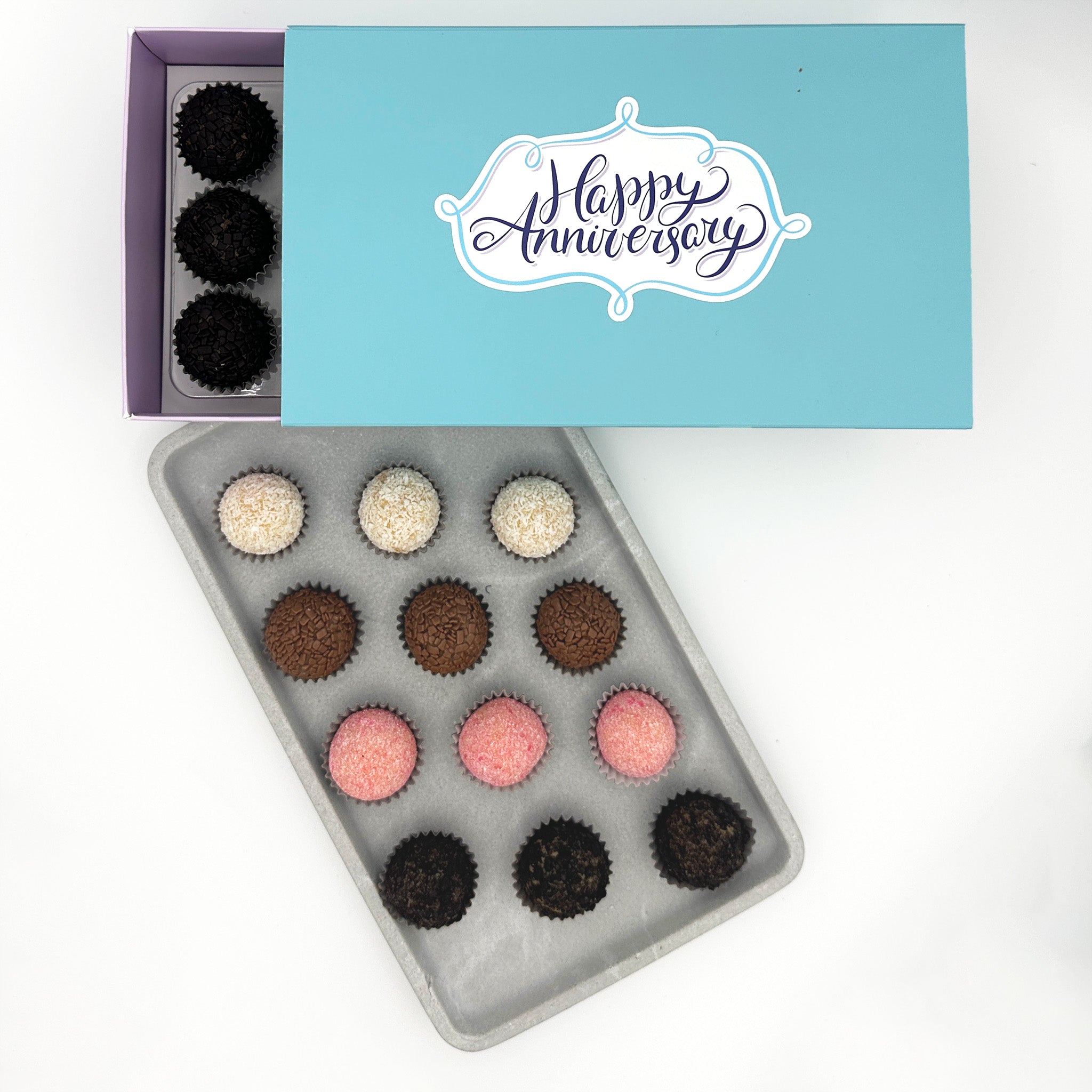 A box of Anniversary Classic Brigadeiros truffles with the words happy anniversary, available in a variety of flavors.