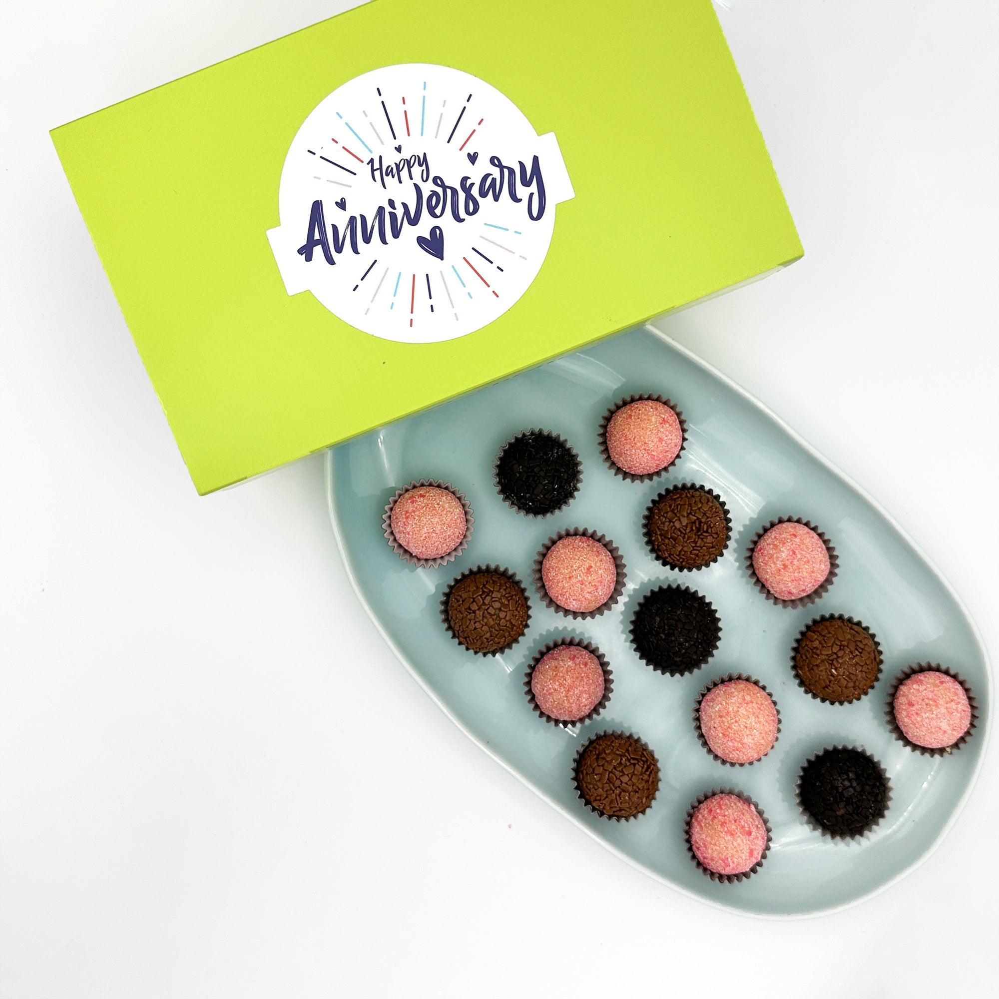 A box of Anniversary Chocolate + Strawberries Brigadeiros with "happy anniversary" written on it.