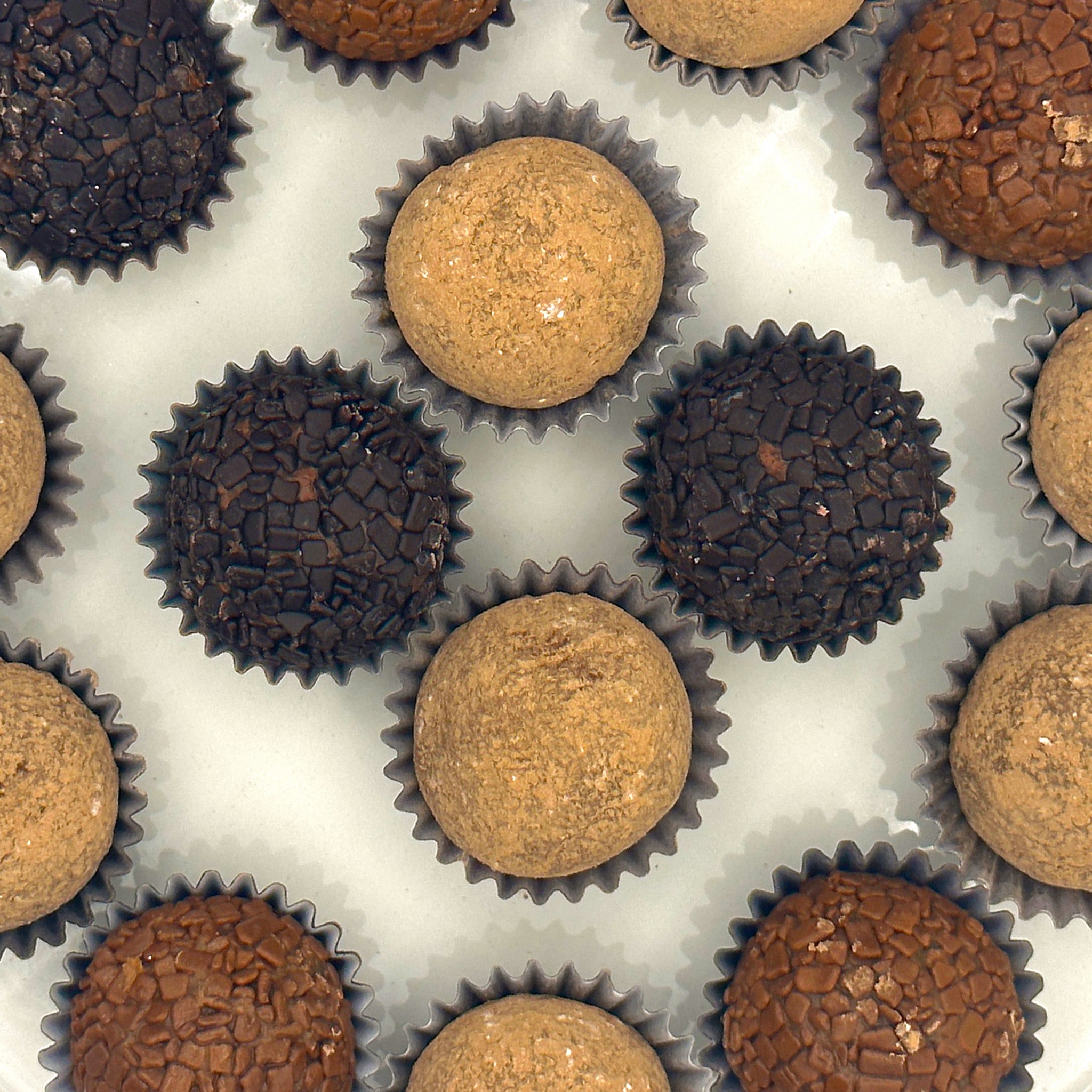 A group of Anniversary Coffee + Chocolate Brigadeiros on a white surface, perfect for the anniversary celebration.